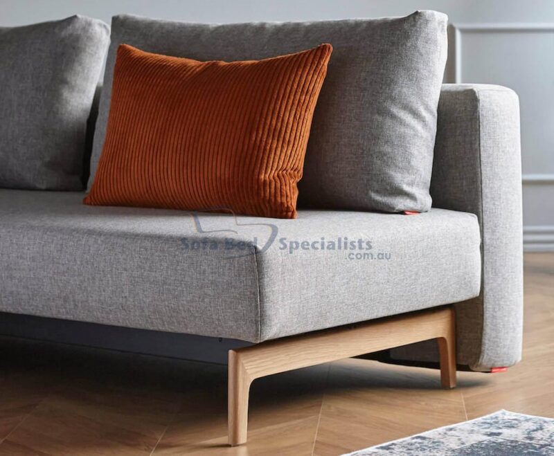 Trym Sleek Sofa Bed in 521 Mixed Grey with an orange cushion